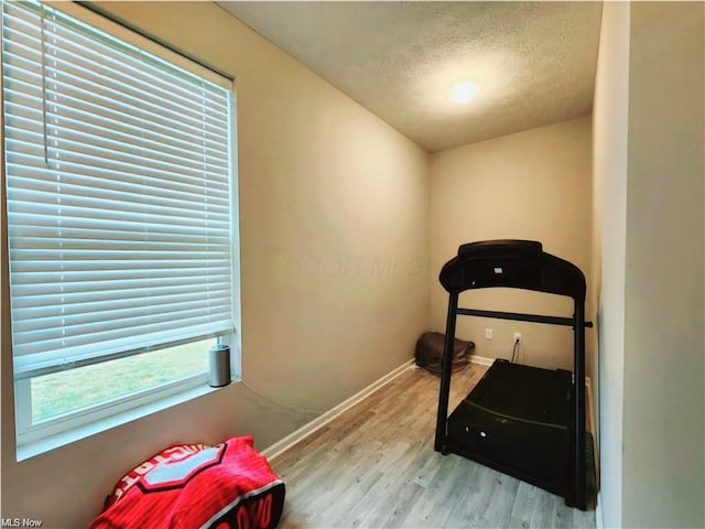 exercise room featuring light hardwood / wood-style floors and a textured ceiling