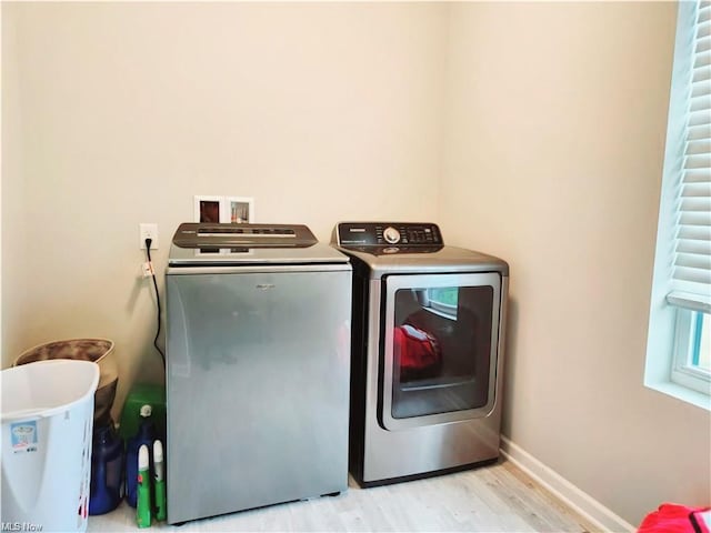 clothes washing area with separate washer and dryer and light hardwood / wood-style flooring