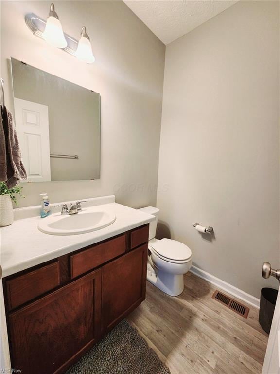 bathroom featuring vanity, a textured ceiling, wood-type flooring, and toilet