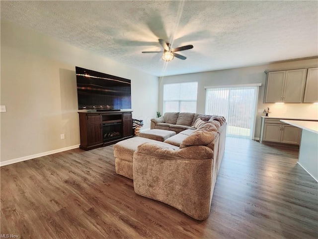 living room with ceiling fan, dark wood-type flooring, and a textured ceiling