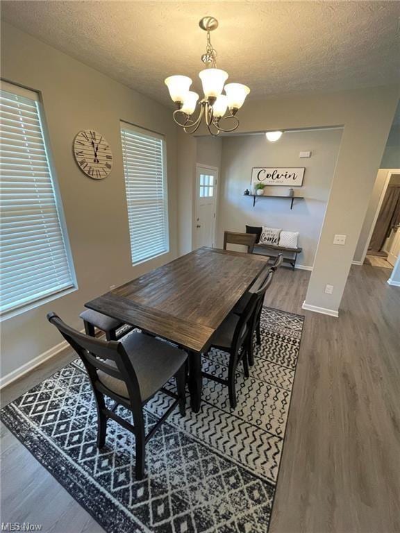 dining area with an inviting chandelier, hardwood / wood-style floors, and a textured ceiling