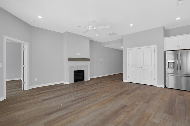 unfurnished living room featuring a tiled fireplace, ceiling fan, and hardwood / wood-style flooring