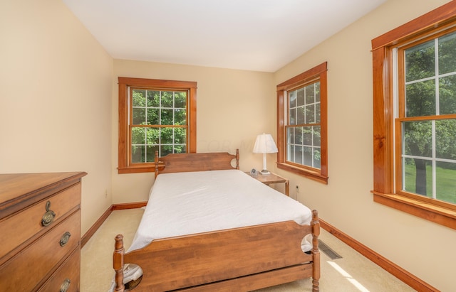 bedroom with light carpet and multiple windows