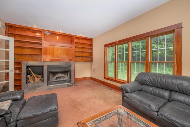 living room with carpet, built in shelves, and a tile fireplace