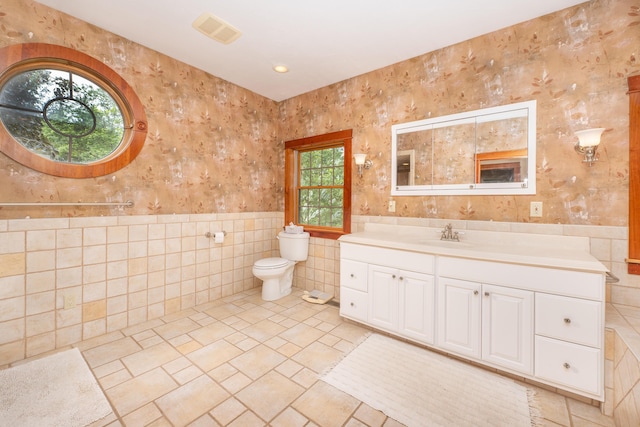 bathroom featuring vanity, toilet, and tile walls