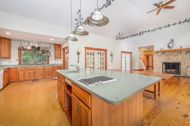 kitchen featuring white appliances, sink, hanging light fixtures, a fireplace, and an island with sink