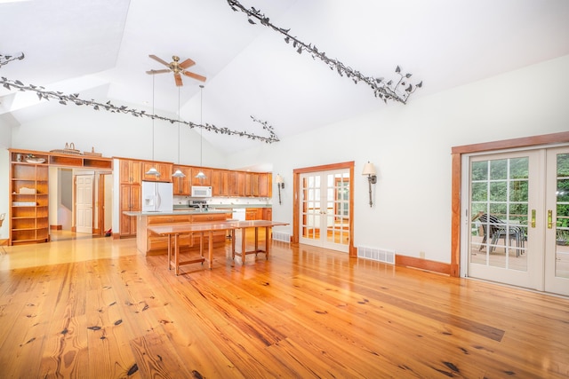 unfurnished dining area with french doors, light hardwood / wood-style floors, high vaulted ceiling, and ceiling fan