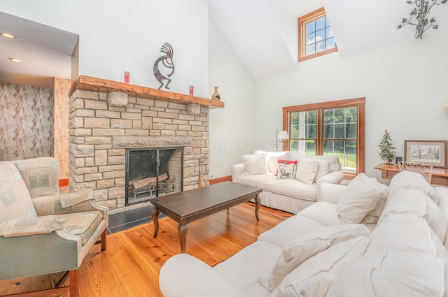 living room featuring hardwood / wood-style floors, a stone fireplace, and high vaulted ceiling