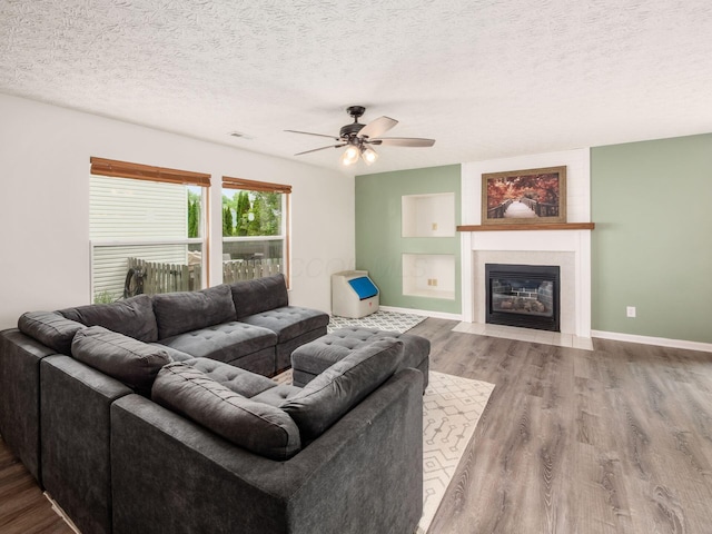 2124 Ripple Rd, Hilliard, OH 43026 - living room featuring wood finished floors, ceiling fan, a textured ceiling, a fireplace with flush hearth, and baseboards