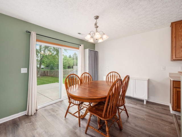 2124 Ripple Rd, Hilliard, OH 43026 - dining space featuring a chandelier, dark wood finished floors, baseboards, and a textured ceiling