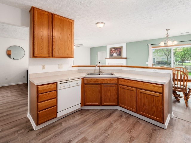 2124 Ripple Rd, Hilliard, OH 43026 - kitchen with dishwasher, a sink, light wood-style floors, a peninsula, and light countertops