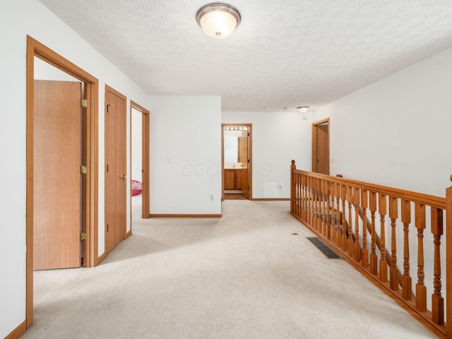 2124 Ripple Rd, Hilliard, OH 43026 - hall featuring an upstairs landing, carpet flooring, a textured ceiling, and baseboards