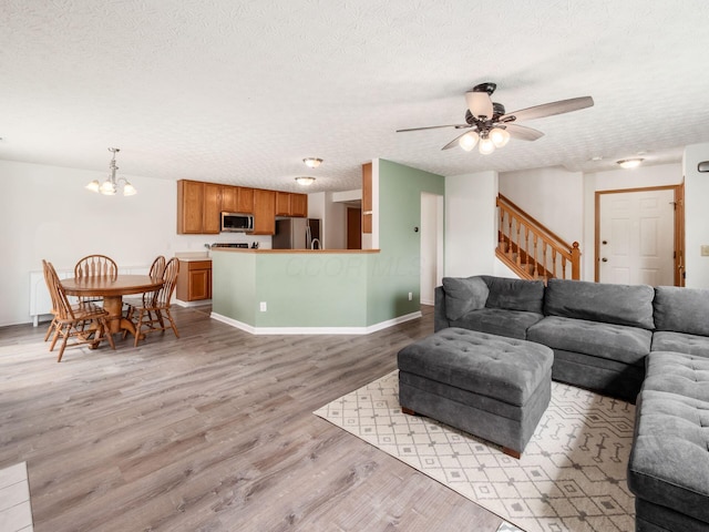 2124 Ripple Rd, Hilliard, OH 43026 - living room featuring a textured ceiling, light wood-type flooring, a chandelier, stairs, and a ceiling fan