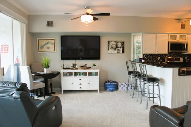 carpeted living room featuring ceiling fan and ornamental molding