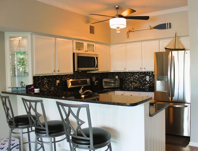 kitchen featuring white cabinets, a breakfast bar, stainless steel appliances, and kitchen peninsula