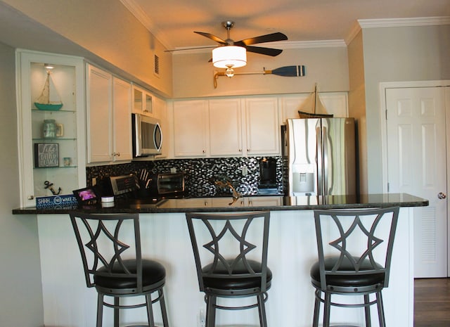 kitchen featuring a kitchen breakfast bar, kitchen peninsula, crown molding, and stainless steel appliances