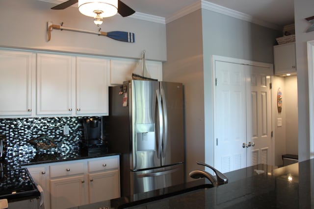 kitchen with white cabinets, decorative backsplash, stainless steel fridge, and dark stone countertops