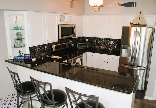 kitchen featuring dark stone countertops, white cabinetry, and appliances with stainless steel finishes