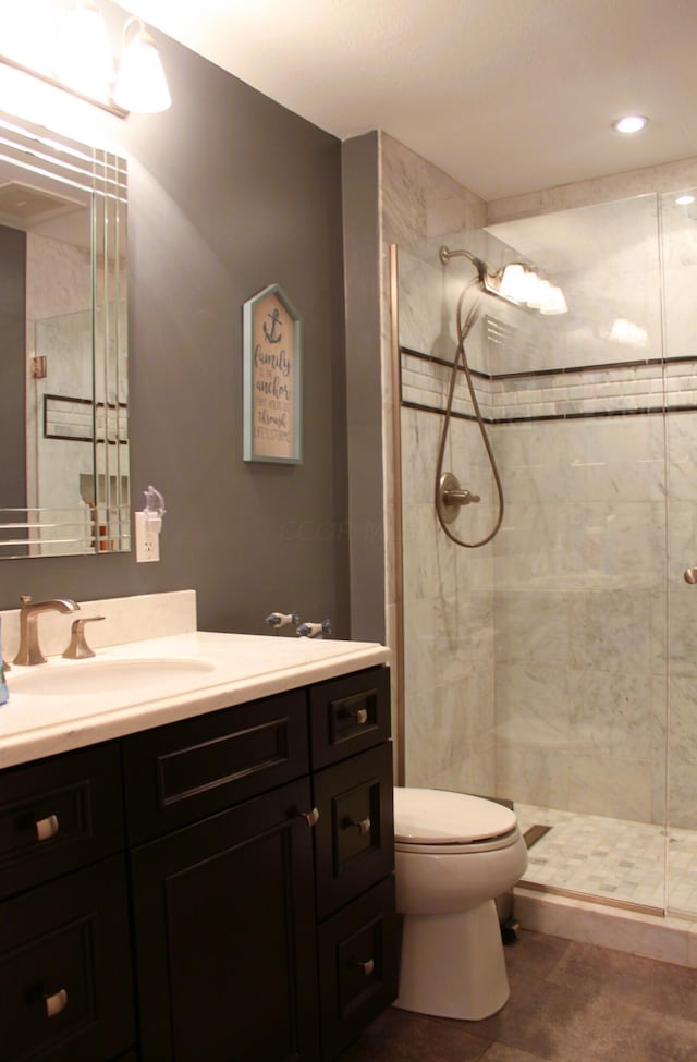 bathroom with tile patterned flooring, a tile shower, vanity, and toilet