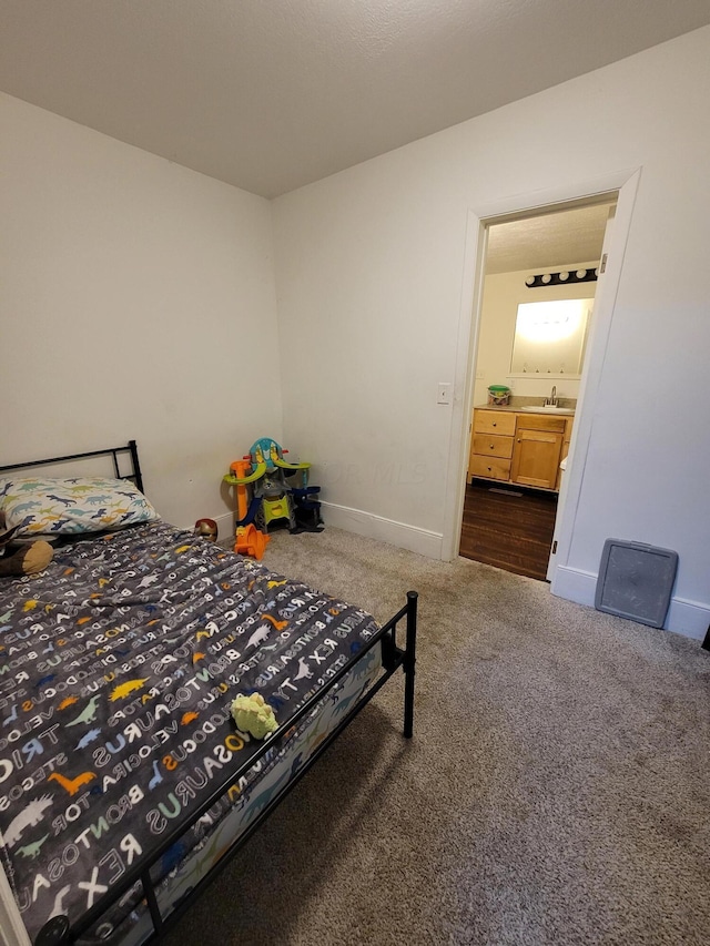 bedroom with ensuite bath, sink, and carpet