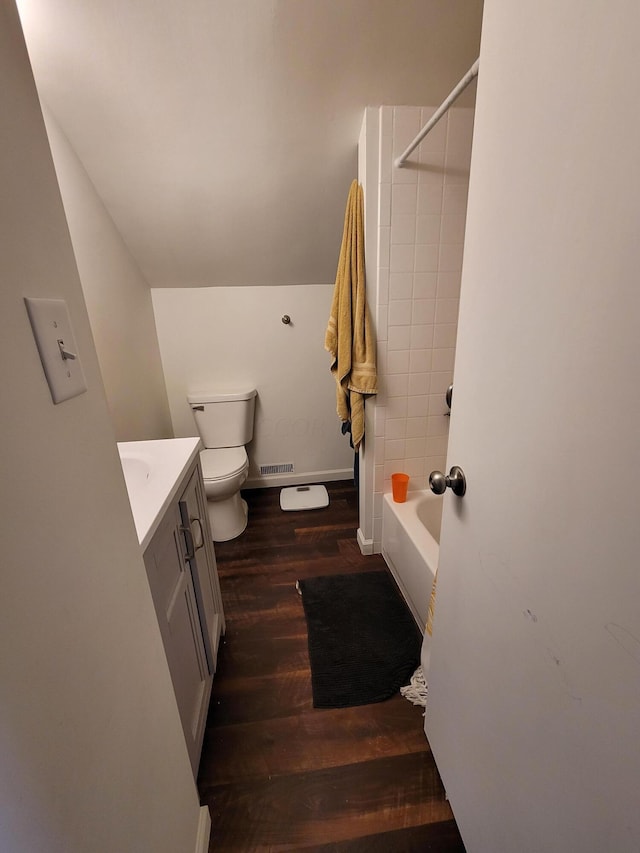 full bathroom featuring vanity, tiled shower / bath, vaulted ceiling, toilet, and wood-type flooring