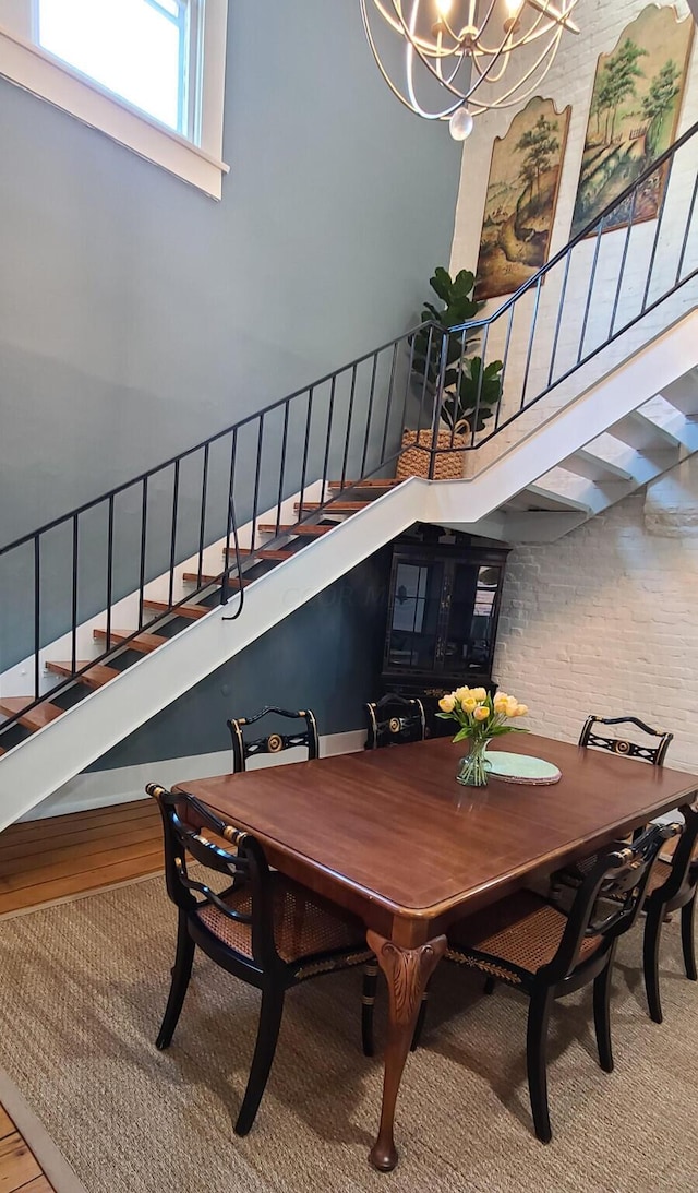 dining area featuring hardwood / wood-style floors, a notable chandelier, and a towering ceiling