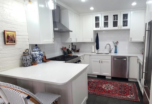 kitchen with kitchen peninsula, decorative backsplash, stainless steel appliances, wall chimney range hood, and white cabinetry