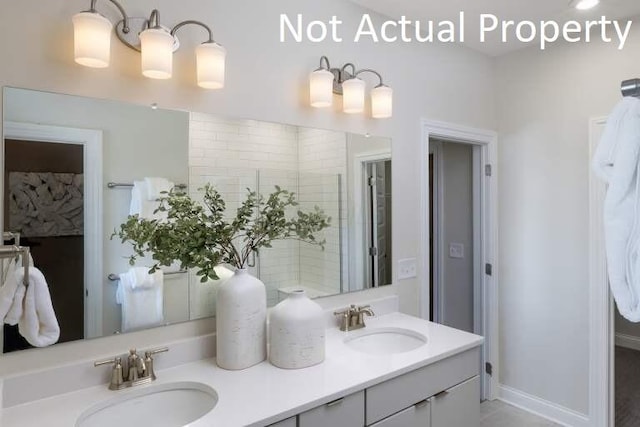 full bathroom featuring double vanity, a sink, and baseboards