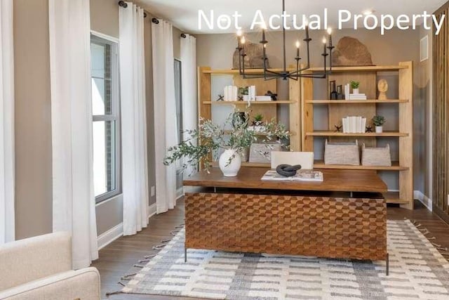 interior space featuring baseboards, wood finished floors, and a notable chandelier