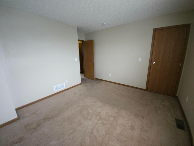 empty room featuring a textured ceiling and light colored carpet