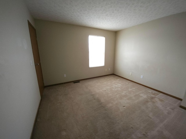 empty room featuring light carpet and a textured ceiling