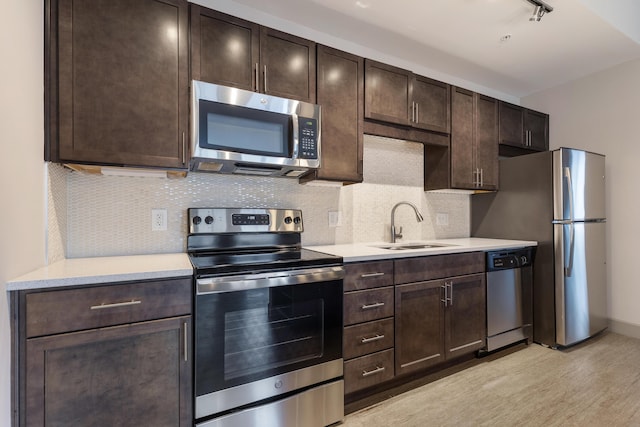 kitchen featuring sink, stainless steel appliances, tasteful backsplash, light hardwood / wood-style floors, and dark brown cabinets