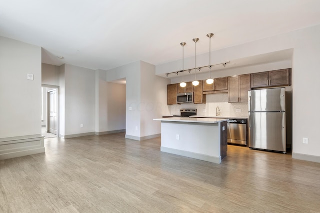 kitchen featuring a center island, stainless steel appliances, light hardwood / wood-style flooring, decorative light fixtures, and decorative backsplash