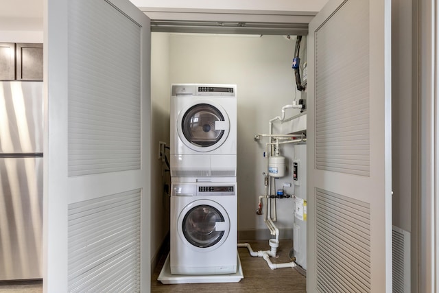 laundry area featuring stacked washer / dryer, water heater, and dark hardwood / wood-style floors