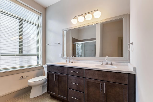 bathroom featuring vanity, a shower with shower door, and toilet