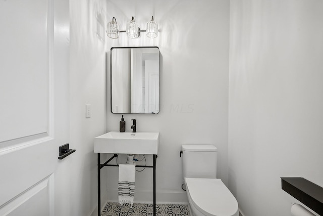 bathroom with baseboards, a sink, and toilet