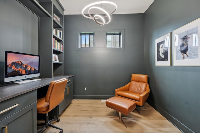 office space featuring light wood-style floors, a notable chandelier, and baseboards