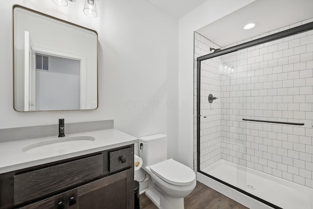 bathroom with toilet, a stall shower, wood finished floors, and vanity