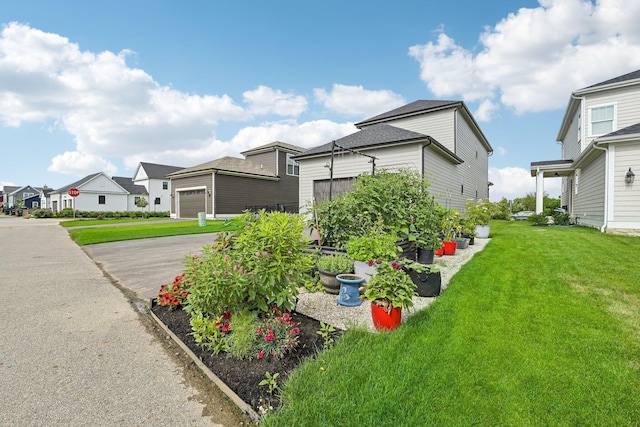 exterior space featuring an attached garage, driveway, a front yard, and a residential view