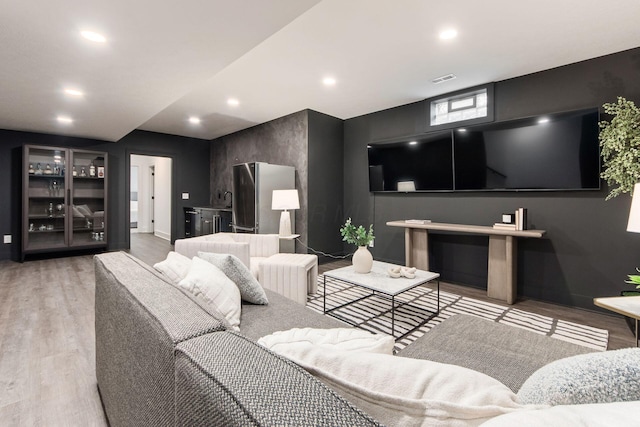 living room with baseboards, recessed lighting, visible vents, and light wood-style floors