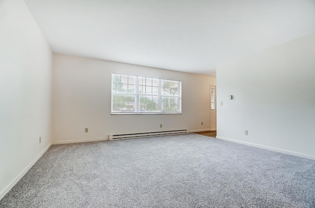 carpeted empty room featuring a baseboard heating unit