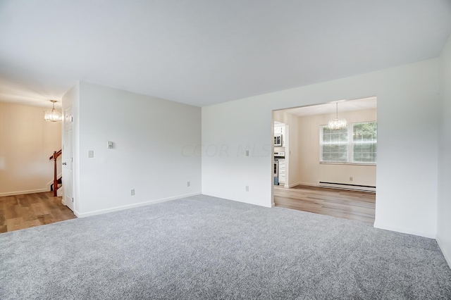 spare room featuring a chandelier, light hardwood / wood-style flooring, and a baseboard heating unit