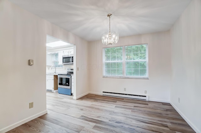 unfurnished dining area with a chandelier, light wood-type flooring, a baseboard heating unit, and sink