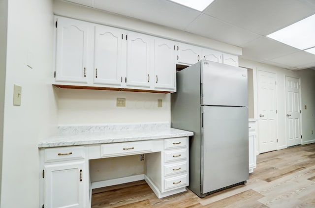 kitchen featuring a drop ceiling, stainless steel fridge, light hardwood / wood-style floors, and white cabinetry