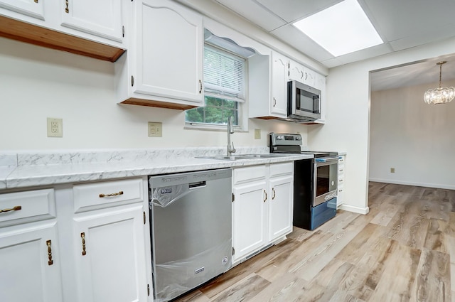 kitchen featuring white cabinets, decorative light fixtures, stainless steel appliances, and light hardwood / wood-style flooring