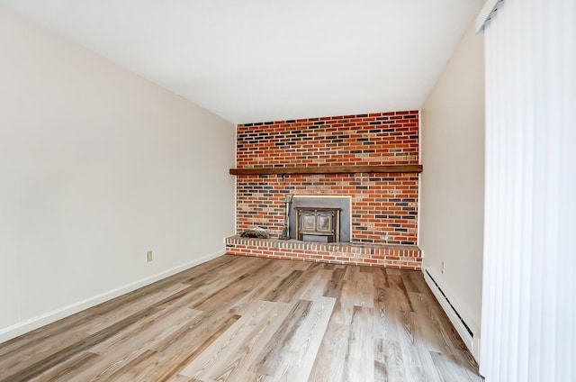 unfurnished living room with a wood stove, a baseboard radiator, and light hardwood / wood-style floors