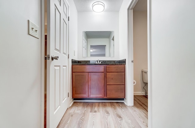 bathroom with vanity, a textured ceiling, hardwood / wood-style flooring, and toilet