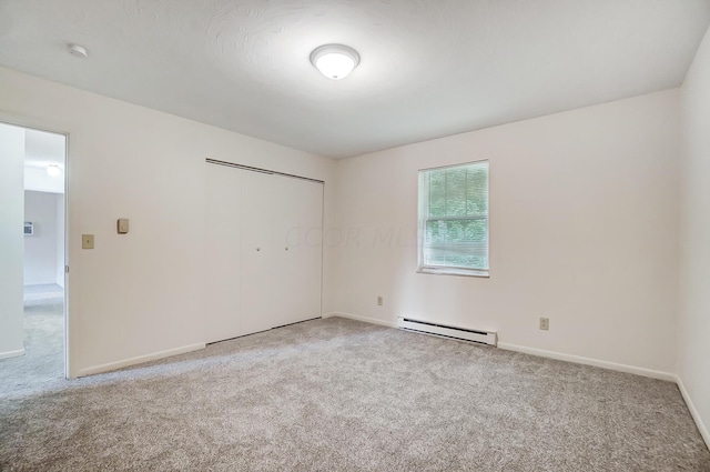 spare room with baseboard heating and light colored carpet