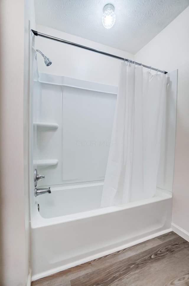 bathroom with shower / tub combo, wood-type flooring, and a textured ceiling