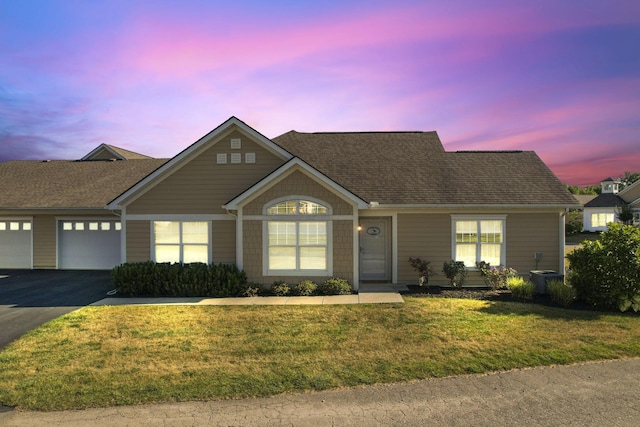 view of front of home with a lawn, a garage, and central AC